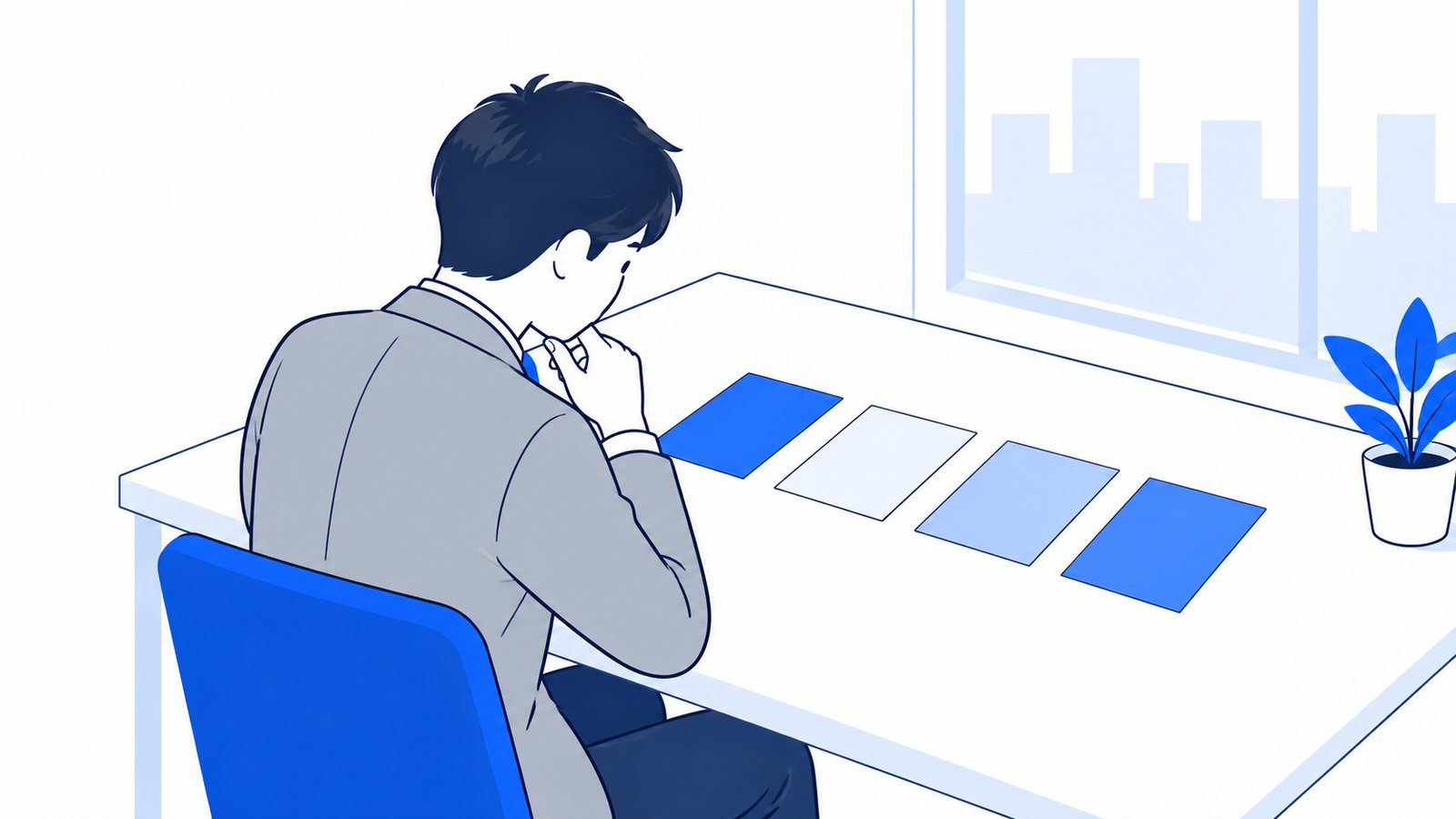 机に4枚のカードを並べて、どれを使うか検討している会社員