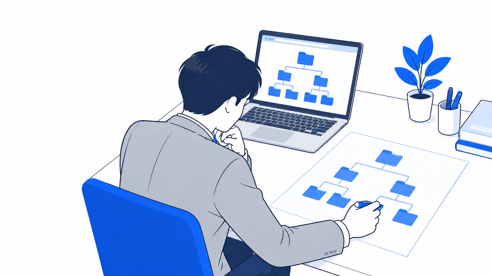 机の上でフォルダの階層図を描いて確かめる担当者とノートPC