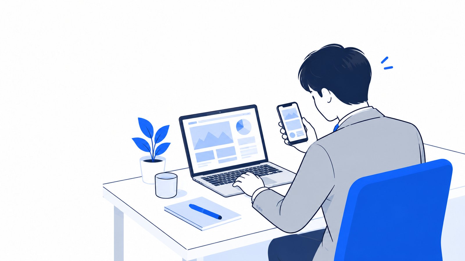 デスクのノートPCとスマホを見比べて、どの端末で作業を進めるか確かめている会社員